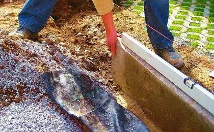 Handwerker richtet eine Kante mit der Wasserwaage aus. Stabile Einfassung für Pflastersteine bei Pflasterarbeiten.