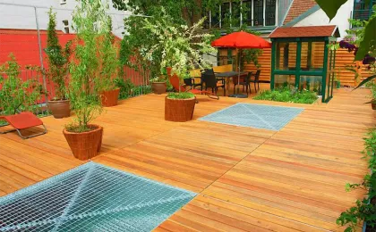 Eine große Holzterrasse mit integrierten Metallgittern und Kübelpflanzen. Moderne Terrassen aus Holz im urbanen Raum.