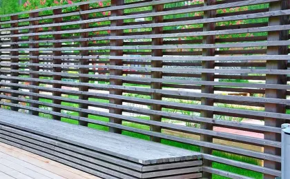 Ein moderner Sichtschutz aus horizontalen Holzlamellen schützt eine Terrasse. Stilvolle Zäune für mehr Privatsphäre.